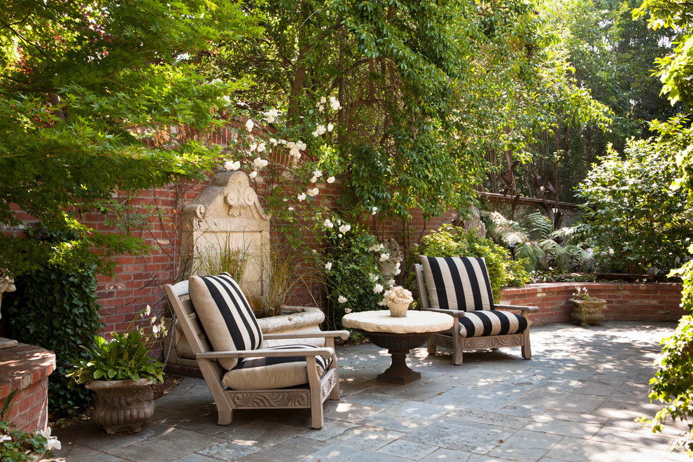 Mid-sized traditional courtyard patio in San Francisco with a water feature and natural stone pavers.