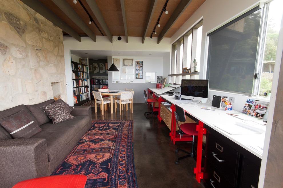 Large eclectic home office in Sunshine Coast with white walls, concrete floors and a built-in desk.