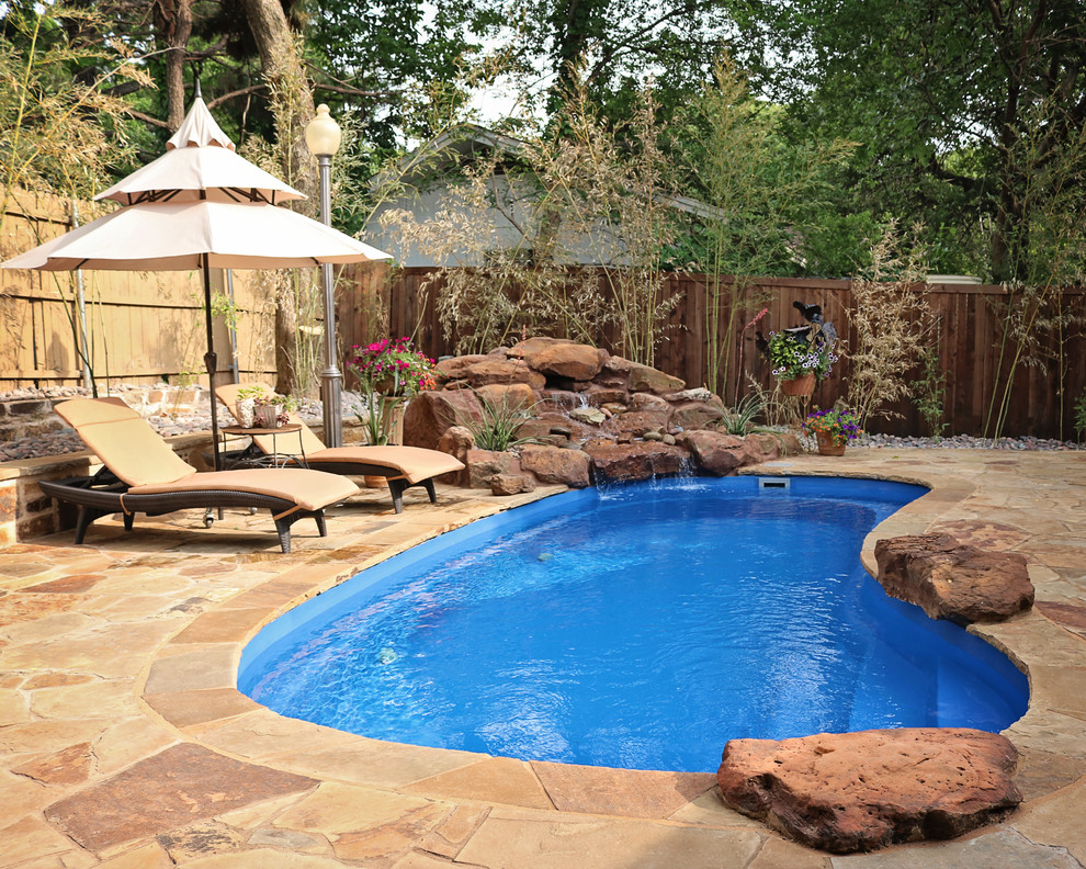 Mid-sized traditional backyard kidney-shaped natural pool in Dallas with a water feature and natural stone pavers.