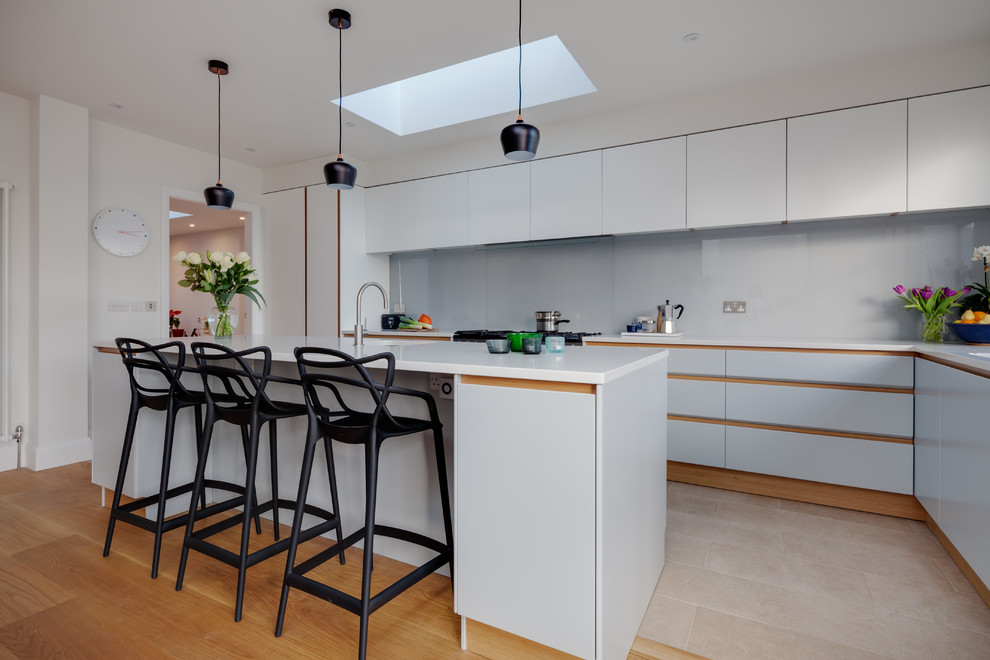 Large contemporary l-shaped separate kitchen in Cambridgeshire with a drop-in sink, flat-panel cabinets, grey cabinets, solid surface benchtops, grey splashback, glass sheet splashback, ceramic floors and with island.