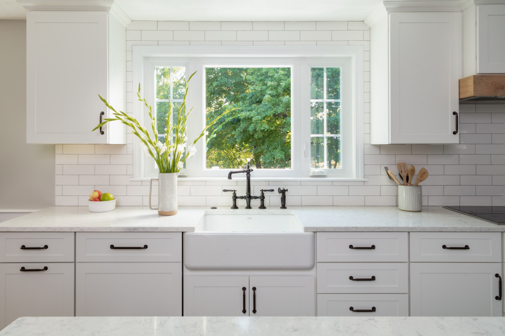 Exempel på ett klassiskt vit vitt kök och matrum, med en rustik diskho, skåp i shakerstil, vita skåp, bänkskiva i kvarts, vitt stänkskydd, stänkskydd i tunnelbanekakel, rostfria vitvaror, mellanmörkt trägolv och en köksö