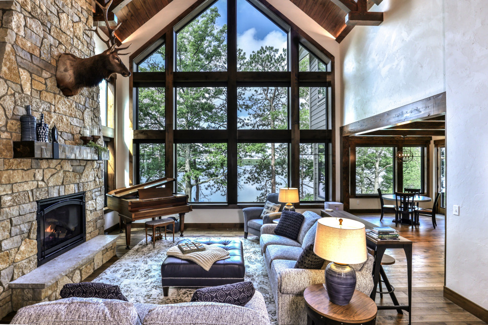 Inspiration pour un grand salon traditionnel ouvert avec un sol en bois brun, une cheminée standard, un manteau de cheminée en pierre, un sol marron et un plafond voûté.