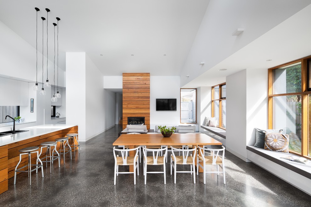This is an example of a mid-sized contemporary open plan dining in Melbourne with white walls, concrete floors, grey floor, a standard fireplace and a wood fireplace surround.