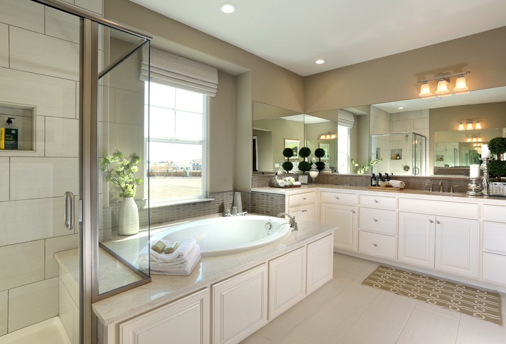 This is an example of a mid-sized beach style master bathroom in San Francisco with an undermount sink, raised-panel cabinets, white cabinets, engineered quartz benchtops, a drop-in tub, beige tile, stone tile, beige walls and ceramic floors.