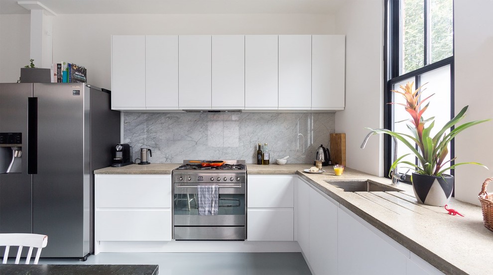 Photo of a mid-sized contemporary l-shaped eat-in kitchen in Perth with a drop-in sink, flat-panel cabinets, white cabinets, concrete benchtops, white splashback, marble splashback, stainless steel appliances, vinyl floors and no island.