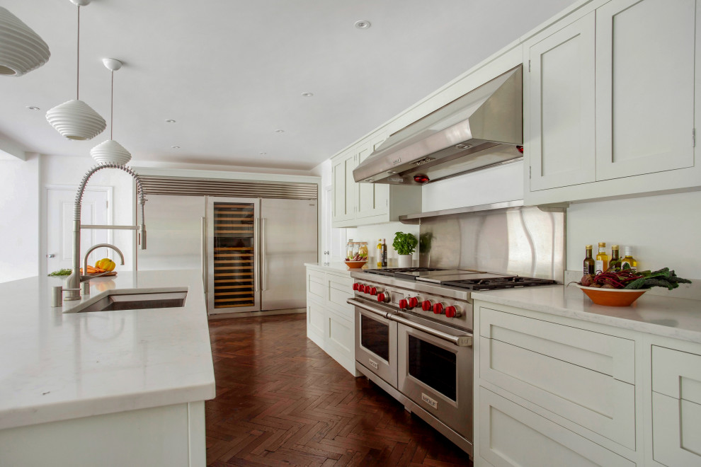Bild på ett stort vintage vit vitt kök, med en undermonterad diskho, skåp i shakerstil, gröna skåp, bänkskiva i kvartsit, rostfria vitvaror, mellanmörkt trägolv, en köksö och brunt golv