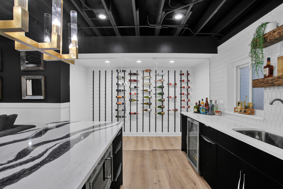 Photo of a large modern basement in Chicago with a home bar, black walls, a wooden fireplace surround and exposed beams.