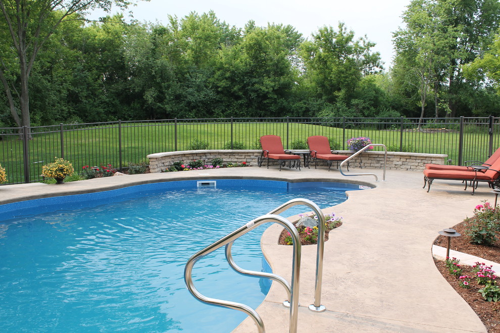 Large traditional backyard custom-shaped pool in Chicago with concrete slab.
