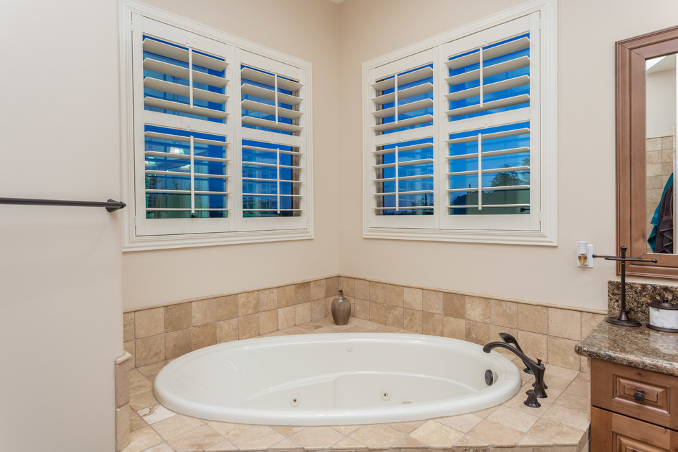 Large country master bathroom in Phoenix with a drop-in sink, recessed-panel cabinets, medium wood cabinets, granite benchtops, a corner tub, an open shower, a one-piece toilet, beige tile, terra-cotta tile, beige walls and terra-cotta floors.