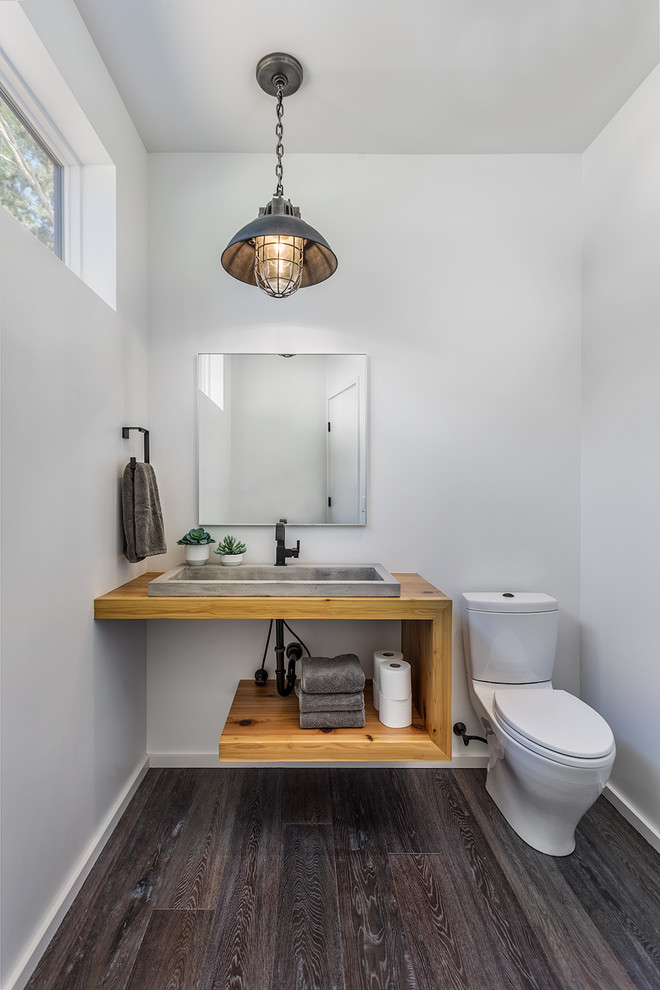 Photo of a country powder room in Other with open cabinets, light wood cabinets, a two-piece toilet, white walls, dark hardwood floors, a vessel sink, wood benchtops, brown floor and brown benchtops.