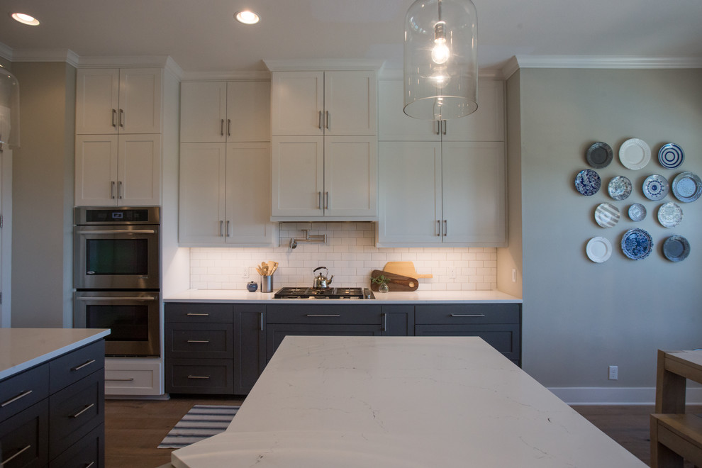 Transitional light wood floor and beige floor eat-in kitchen photo in Austin with a farmhouse sink, shaker cabinets, white cabinets, quartz countertops, white backsplash, subway tile backsplash, stainless steel appliances and an island