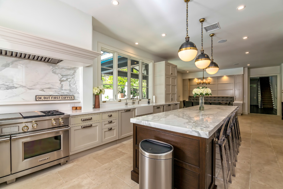 This is an example of an expansive transitional separate kitchen in Los Angeles with grey splashback, with island, a farmhouse sink, shaker cabinets, grey cabinets, quartz benchtops, stone slab splashback, stainless steel appliances, beige floor and grey benchtop.