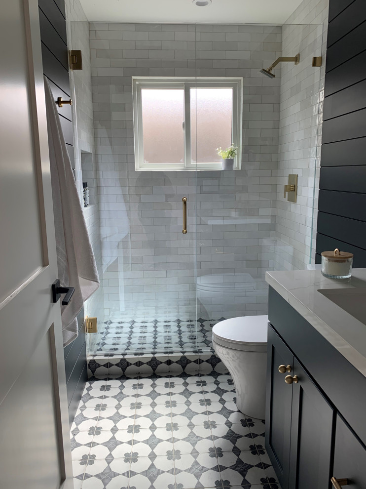 На фото: маленькая ванная комната в стиле кантри с плоскими фасадами, серыми фасадами, душем в нише, унитазом-моноблоком, белой плиткой, керамической плиткой, белыми стенами, полом из керамогранита, душевой кабиной, врезной раковиной, столешницей из искусственного кварца, черным полом, душем с распашными дверями, белой столешницей, нишей, тумбой под одну раковину, встроенной тумбой и стенами из вагонки для на участке и в саду с