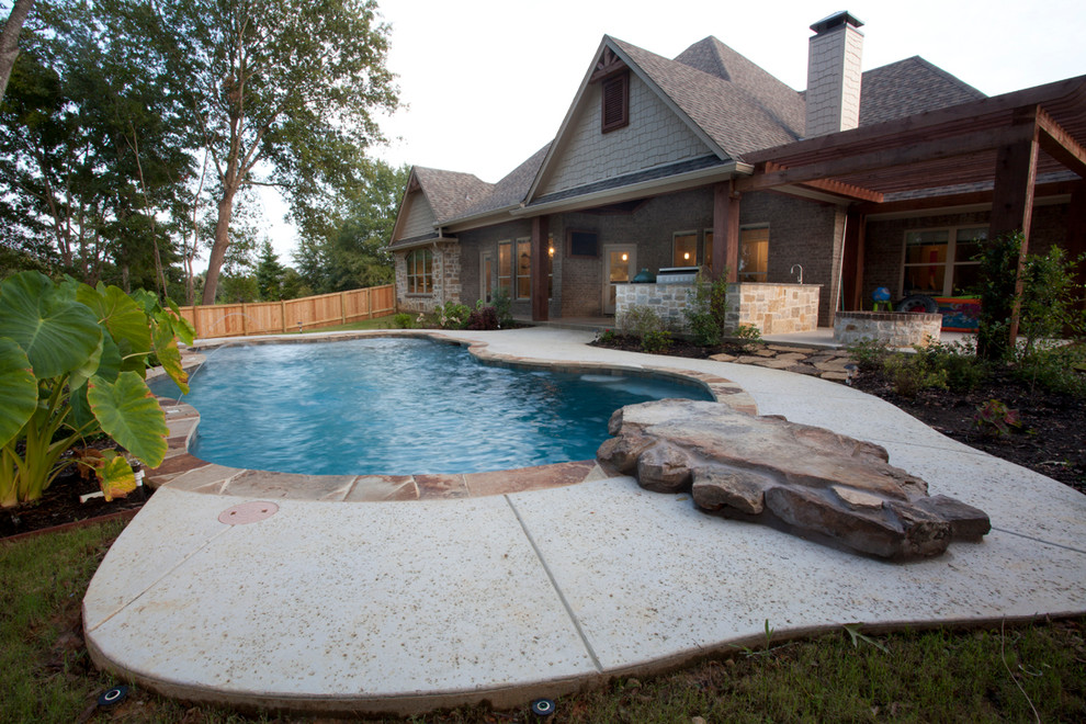 Large arts and crafts backyard custom-shaped pool in Austin with stamped concrete.