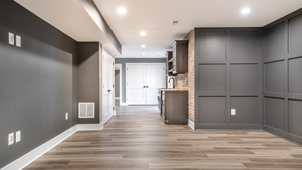 Photo of a mid-sized transitional single-wall wet bar in DC Metro with an undermount sink, shaker cabinets, wood benchtops, red splashback, brick splashback, vinyl floors, brown floor, brown benchtop and grey cabinets.