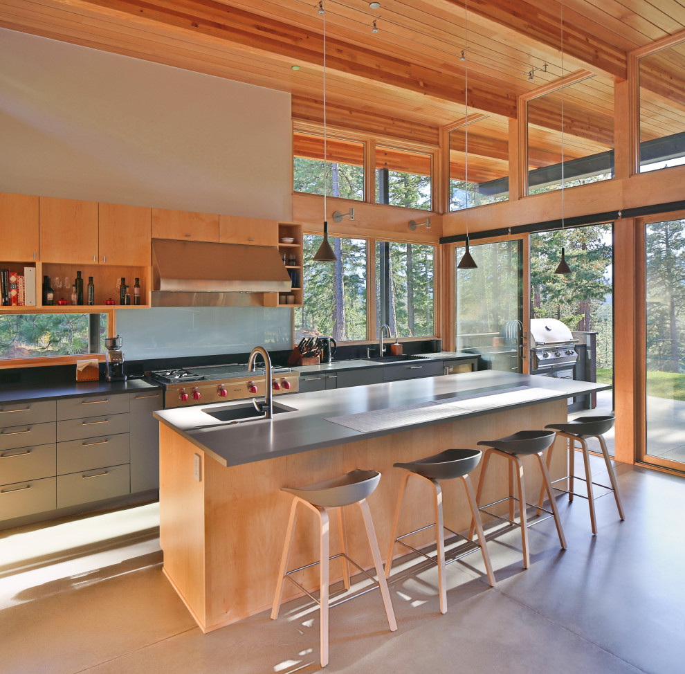 This is an example of a mid-sized country l-shaped open plan kitchen in Seattle with an undermount sink, flat-panel cabinets, light wood cabinets, quartzite benchtops, black splashback, stone slab splashback, stainless steel appliances, concrete floors, with island, grey floor and grey benchtop.