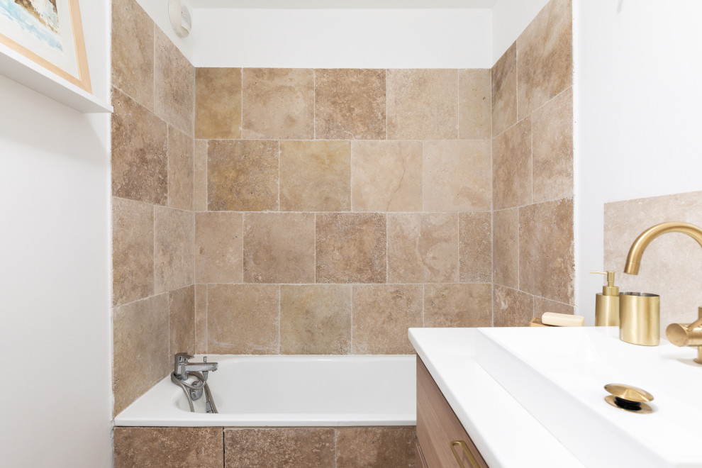 Cette image montre une salle de bain principale méditerranéenne en bois clair de taille moyenne avec un placard à porte affleurante, WC séparés, un carrelage beige, du carrelage en travertin, un mur blanc, un sol en travertin, un sol beige, aucune cabine, un plan de toilette blanc, meuble simple vasque, une baignoire encastrée, un combiné douche/baignoire, un plan de toilette en quartz, meuble-lavabo sur pied et un lavabo posé.