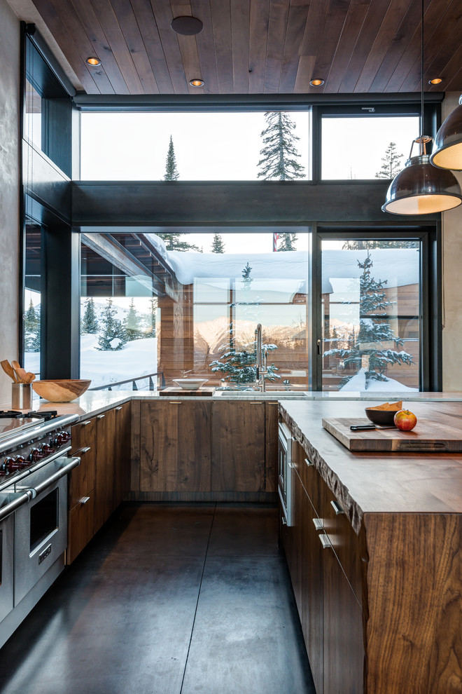 Example of a large mountain style l-shaped concrete floor eat-in kitchen design with an undermount sink, flat-panel cabinets, medium tone wood cabinets, stainless steel appliances, an island and marble countertops