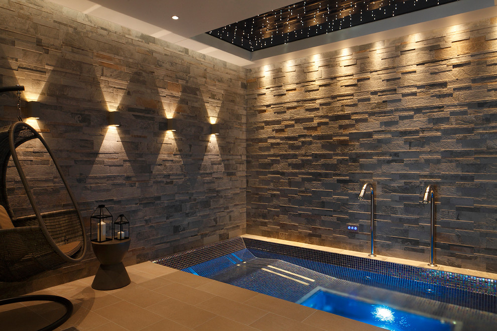 This is an example of a contemporary indoor rectangular pool in London with a hot tub and tile.