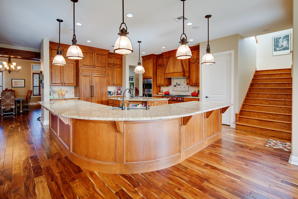 Eat-in kitchen - large transitional l-shaped dark wood floor eat-in kitchen idea in Houston with a double-bowl sink, beaded inset cabinets, medium tone wood cabinets, granite countertops, beige backsplash, stone tile backsplash, paneled appliances and two islands
