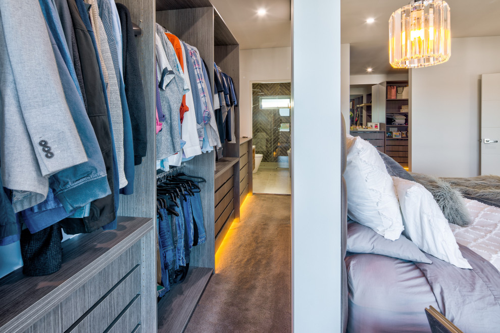 This is an example of a large modern men's walk-in wardrobe in Sydney with carpet and beige floor.