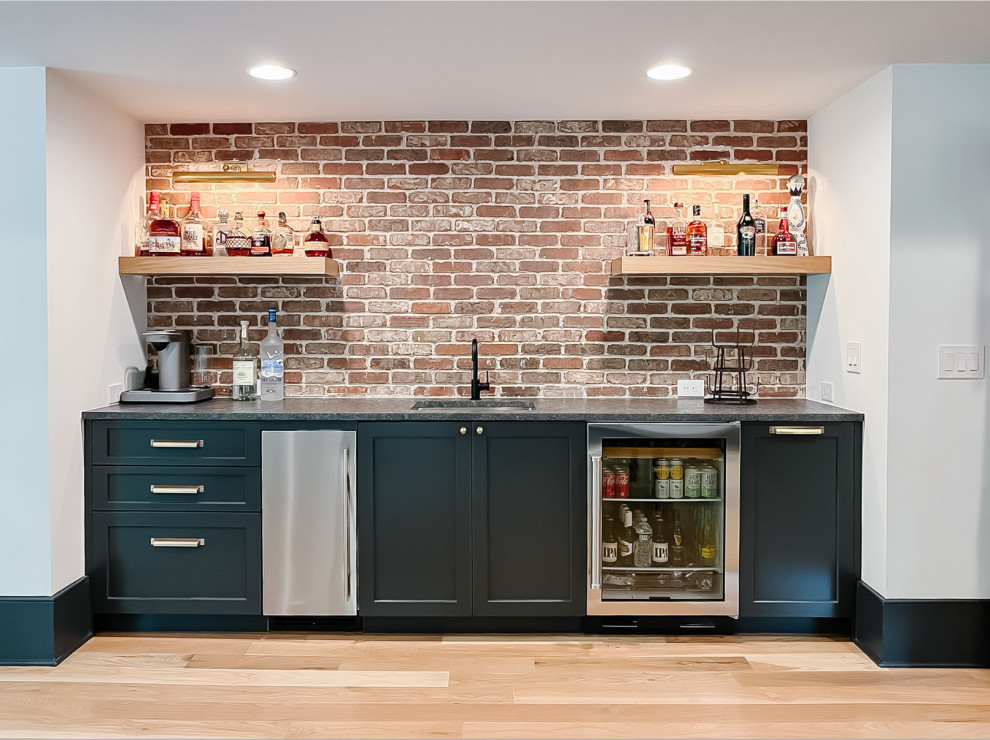 Inspiration for a transitional home bar in Atlanta with an undermount sink, recessed-panel cabinets, black cabinets, granite benchtops, brick splashback, light hardwood floors and grey benchtop.