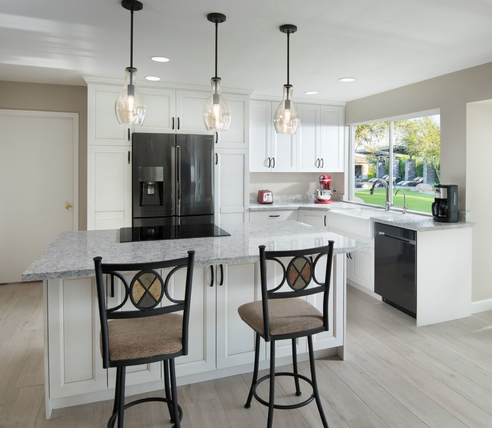 This is an example of a transitional l-shaped kitchen in Phoenix with a farmhouse sink, beaded inset cabinets, white cabinets, granite benchtops, stainless steel appliances, porcelain floors, with island and grey floor.