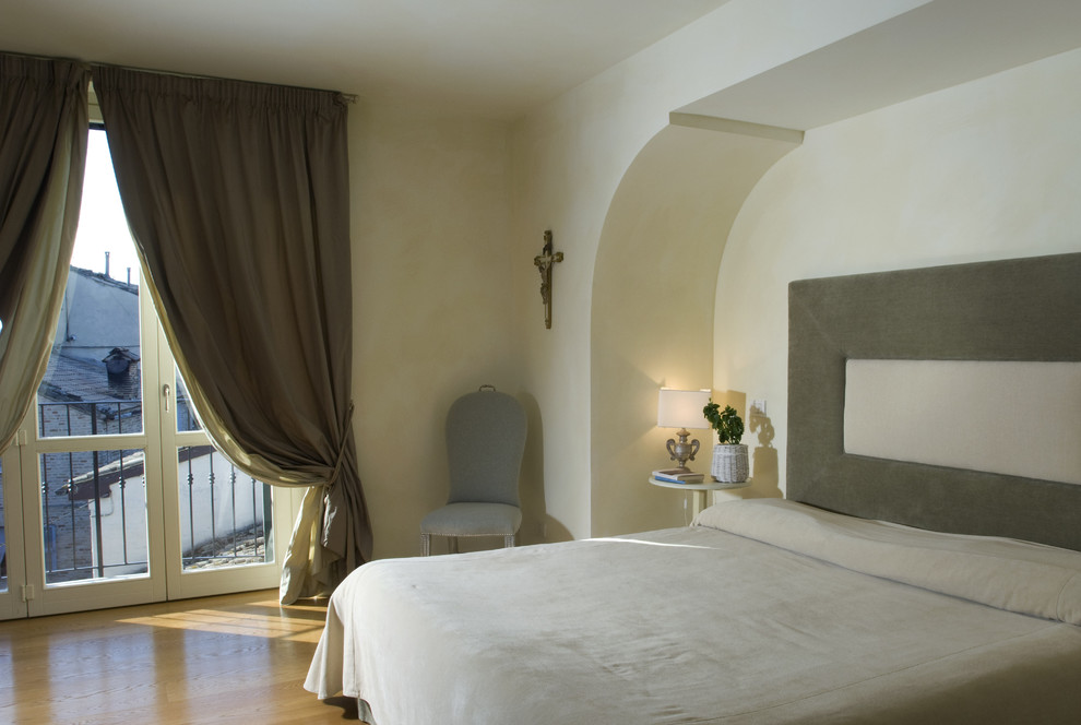 This is an example of a traditional master bedroom in Rome with beige walls and medium hardwood floors.