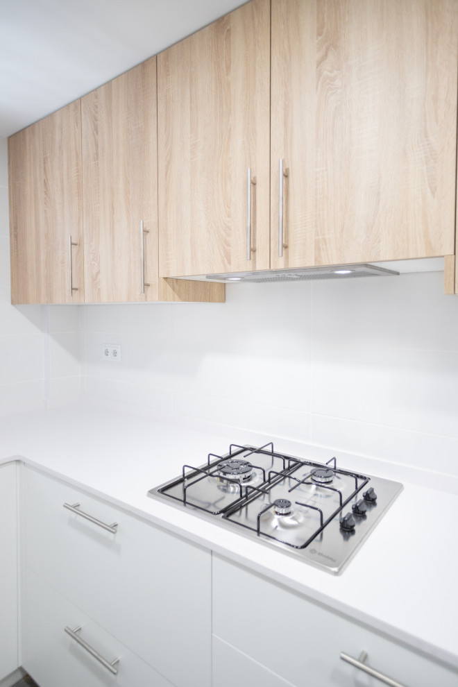 This is an example of a medium sized contemporary l-shaped enclosed kitchen in Barcelona with a double-bowl sink, flat-panel cabinets, white cabinets, white splashback, stainless steel appliances, ceramic flooring, no island, grey floors and white worktops.