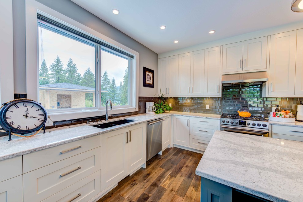 Eat-in kitchen - mid-sized transitional l-shaped medium tone wood floor eat-in kitchen idea in Vancouver with an undermount sink, flat-panel cabinets, gray cabinets, quartz countertops, gray backsplash, glass tile backsplash, stainless steel appliances and an island