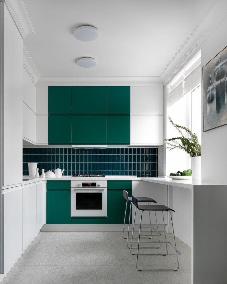 Design ideas for a mid-sized contemporary l-shaped kitchen in Moscow with flat-panel cabinets, green cabinets, green splashback, white appliances, no island, grey floor and white benchtop.