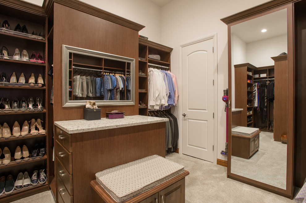 Photo of a large traditional gender-neutral walk-in wardrobe in Denver with flat-panel cabinets, medium wood cabinets, carpet and white floor.