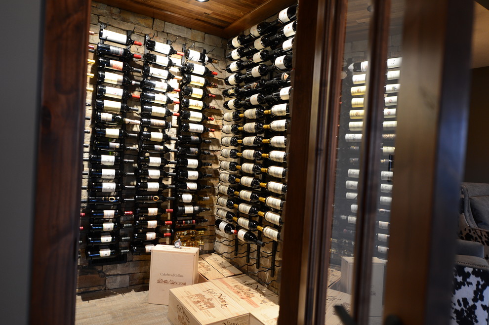 Wine cellar - large transitional walk-out light wood floor wine cellar idea with gray walls, a two-sided fireplace, a stone fireplace and storage racks