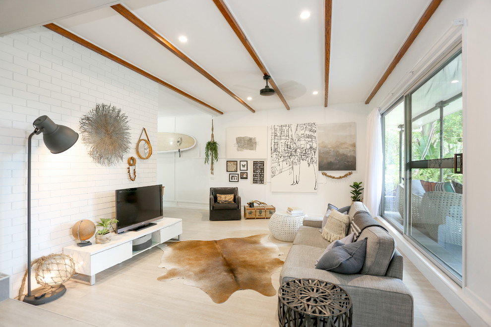 This is an example of a mid-sized beach style enclosed family room in Other with white walls, light hardwood floors, a freestanding tv and beige floor.