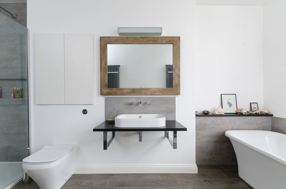 Photo of a contemporary master bathroom in Other with a vessel sink, a freestanding tub, an alcove shower, a wall-mount toilet and white walls.