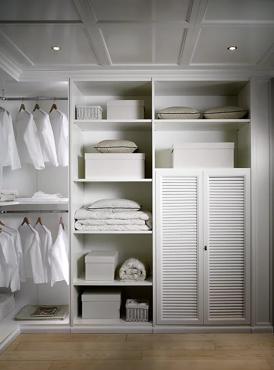 Medium sized gender neutral walk-in wardrobe in New York with louvered cabinets, white cabinets, light hardwood flooring, brown floors and a wood ceiling.