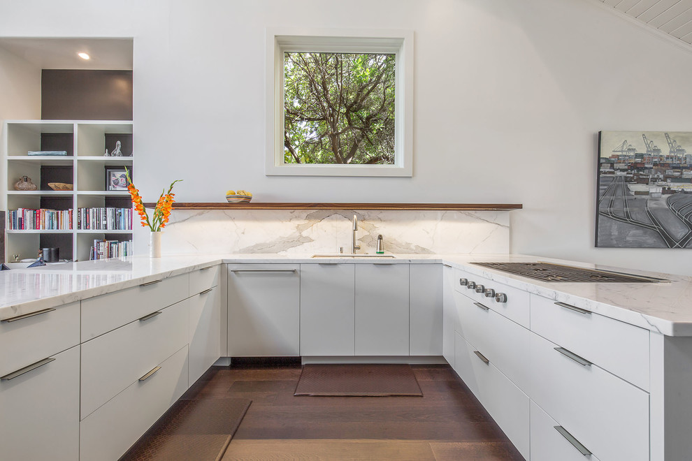 Arts and crafts u-shaped kitchen in San Francisco with an undermount sink, flat-panel cabinets, white cabinets, marble benchtops, white splashback, marble splashback, panelled appliances, medium hardwood floors, a peninsula, brown floor and white benchtop.