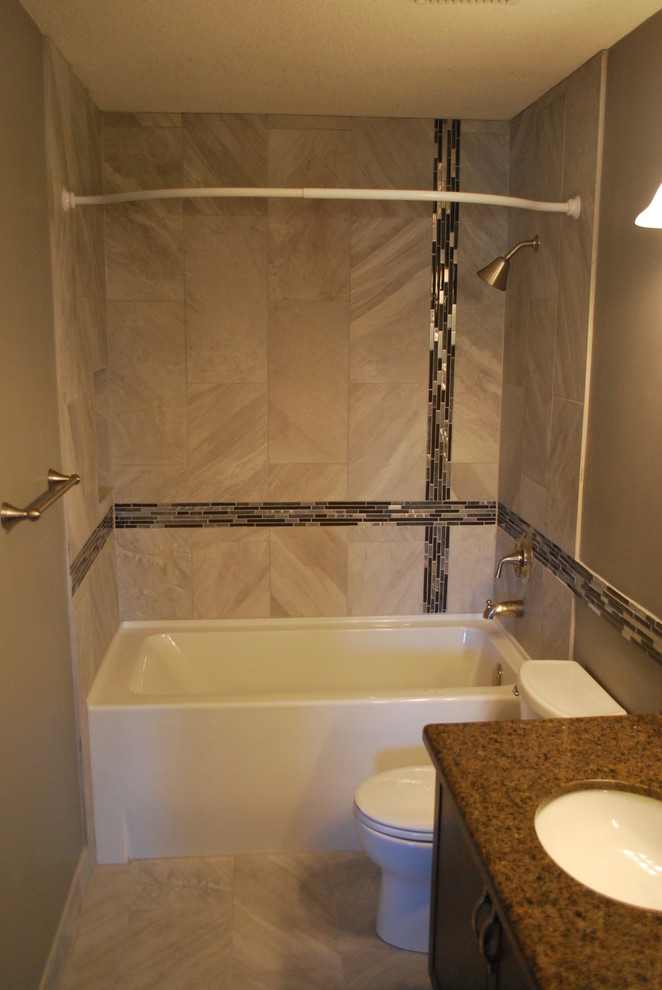 This is an example of a small contemporary 3/4 bathroom in Calgary with shaker cabinets, dark wood cabinets, an alcove tub, a shower/bathtub combo, a two-piece toilet, multi-coloured tile, matchstick tile, beige walls, porcelain floors, an undermount sink, granite benchtops, beige floor and a shower curtain.