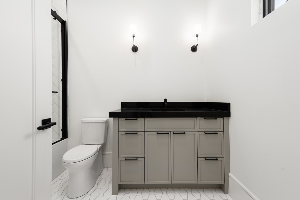 Alcove bathtub - mid-sized transitional ceramic tile, white floor and single-sink alcove bathtub idea with shaker cabinets, gray cabinets, a two-piece toilet, white walls, an undermount sink, quartz countertops, a hinged shower door, black countertops and a built-in vanity