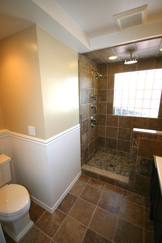 This is an example of a mid-sized traditional 3/4 bathroom in Salt Lake City with a console sink, furniture-like cabinets, dark wood cabinets, marble benchtops, an open shower, a two-piece toilet, brown tile, stone tile, beige walls and travertine floors.