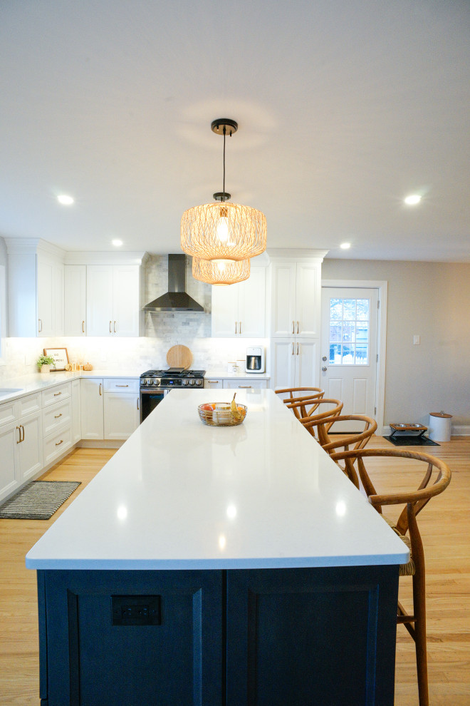 Photo of a transitional eat-in kitchen in Philadelphia with recessed-panel cabinets, white cabinets, quartz benchtops, grey splashback, marble splashback, light hardwood floors, with island, yellow floor and white benchtop.