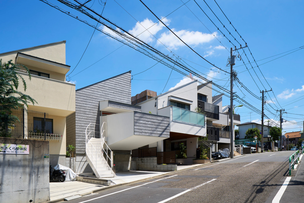 Mittelgroßes, Zweistöckiges Modernes Einfamilienhaus mit Mix-Fassade, grauer Fassadenfarbe, Pultdach, Blechdach, grauem Dach und Verschalung in Tokio