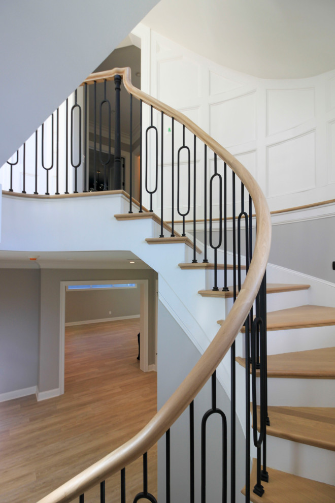 Diseño de escalera curva tradicional renovada extra grande con escalones de madera, contrahuellas de madera, barandilla de varios materiales y boiserie