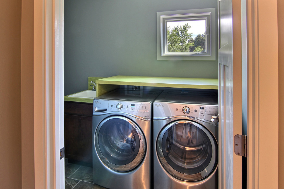 Mid-sized transitional single-wall dedicated laundry room in Other with grey walls, ceramic floors, a side-by-side washer and dryer, a drop-in sink, grey floor and green benchtop.