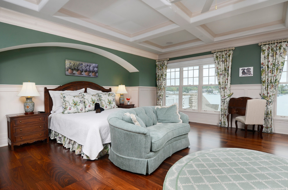Inspiration for a large traditional master bedroom in Other with green walls, brown floor, a standard fireplace, dark hardwood floors and a stone fireplace surround.