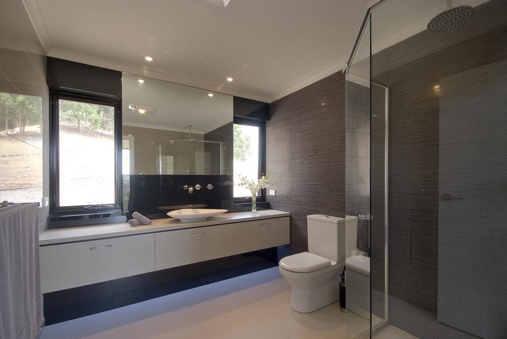 Inspiration for a modern bathroom in Adelaide with flat-panel cabinets, a corner shower, a two-piece toilet, beige tile, brown tile, porcelain tile, ceramic floors, a vessel sink, granite benchtops and a hinged shower door.