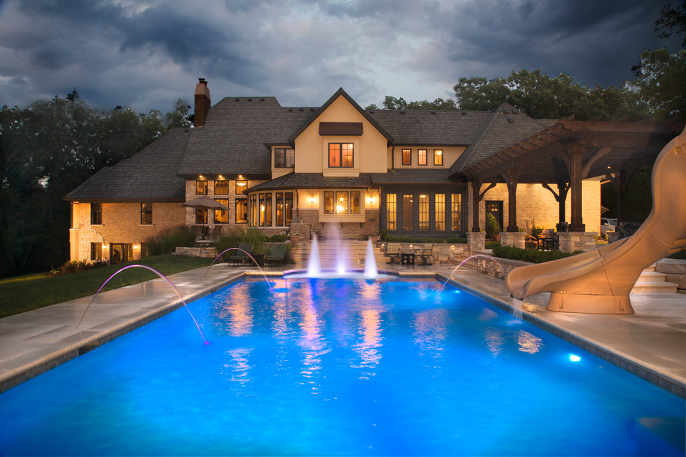 Mid-sized traditional backyard rectangular lap pool in Chicago with a water slide and natural stone pavers.