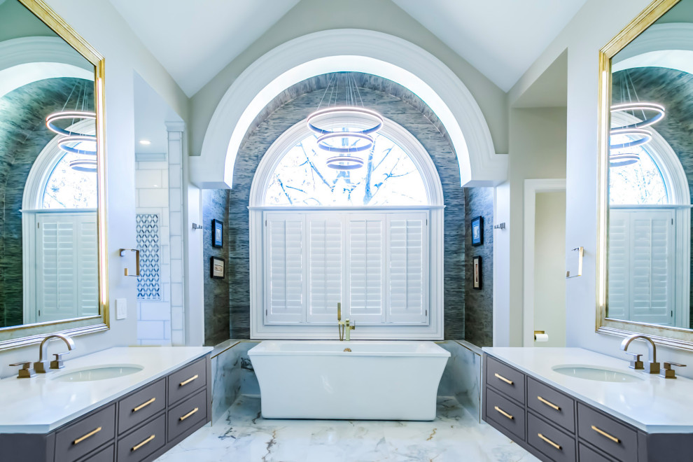 На фото: большой главный совмещенный санузел в современном стиле с плоскими фасадами, синими фасадами, отдельно стоящей ванной, открытым душем, унитазом-моноблоком, разноцветной плиткой, керамической плиткой, бежевыми стенами, полом из керамической плитки, врезной раковиной, столешницей из искусственного кварца, белым полом, открытым душем, белой столешницей, тумбой под две раковины, подвесной тумбой, сводчатым потолком и обоями на стенах с