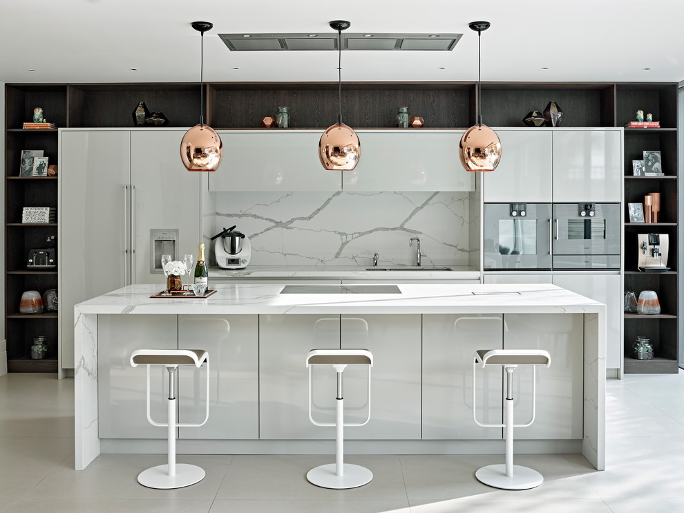 This is an example of a large contemporary kitchen in London with flat-panel cabinets, marble benchtops, white splashback, marble splashback, porcelain floors, with island, an undermount sink, white cabinets, panelled appliances and white floor.
