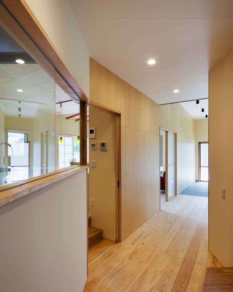 Foto på en mellanstor hall, med beige väggar, ljust trägolv, en skjutdörr och en brun dörr